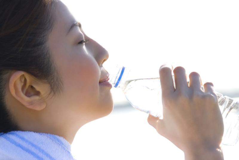 A woman drinking water outdoors.