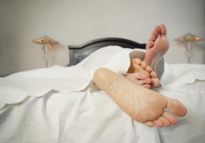A family in bed with barefeet.